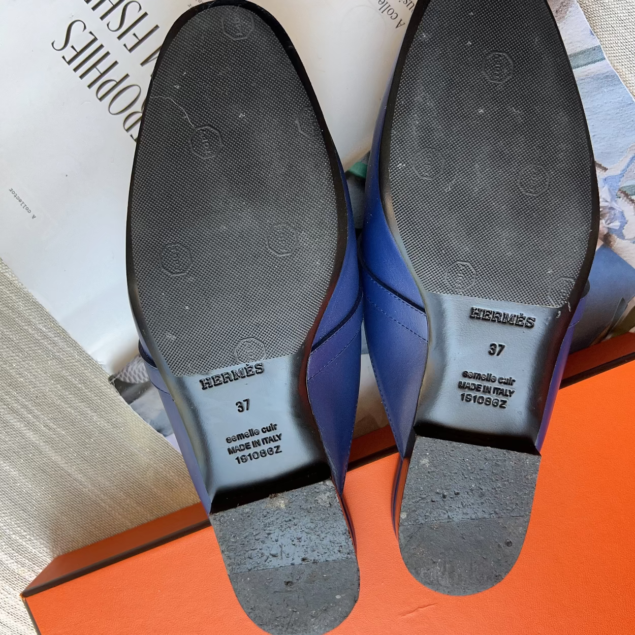 Blue dress shoes with soles facing up on a surface with text and an orange box.