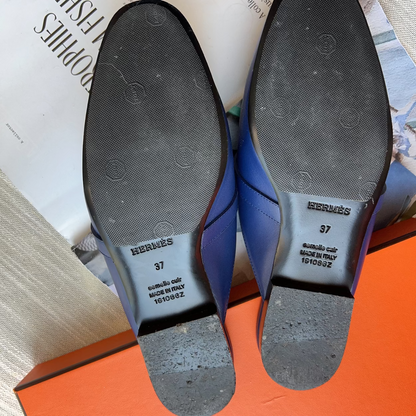 Blue dress shoes with soles facing up on a surface with text and an orange box.