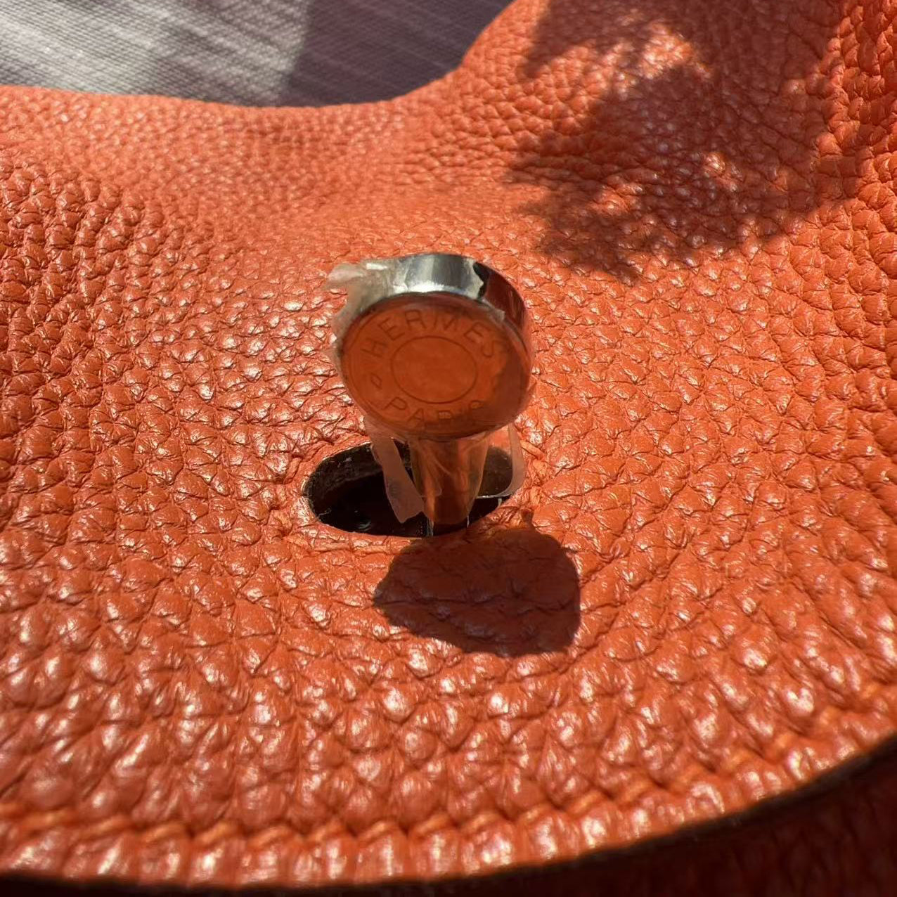 Close-up of a brown leather bag with a metal clasp on a textured surface.