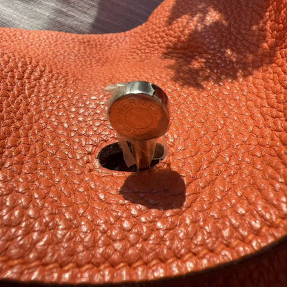 Close-up of a brown leather bag with a metal clasp on a textured surface.