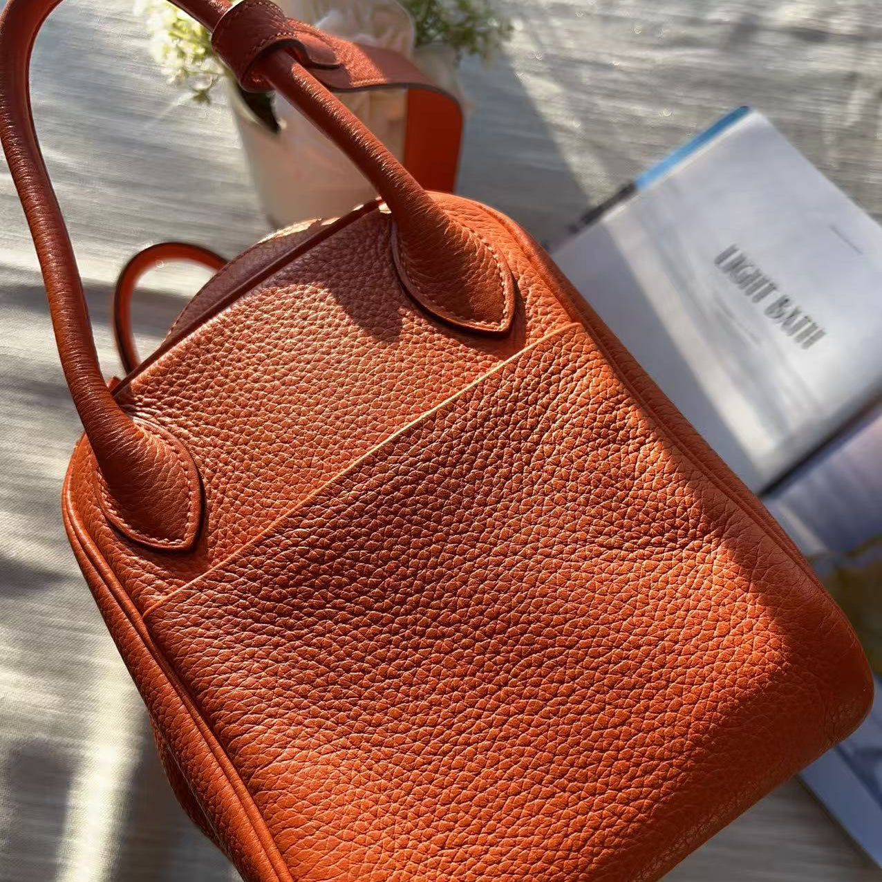 Brown leather handbag on a light wooden surface with a blurred background