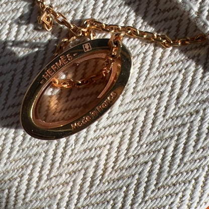 Gold necklace with a pendant on a textured fabric background
