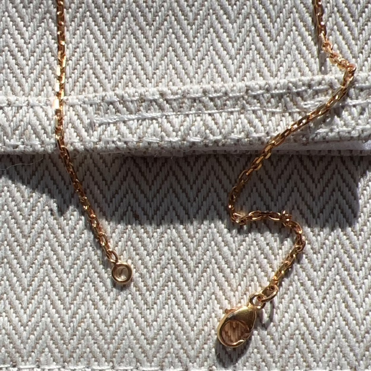 Gold necklace on a textured fabric surface