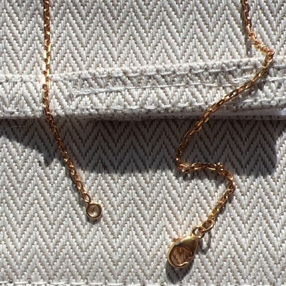 Gold necklace on a textured fabric surface