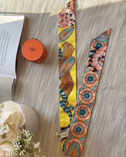 Colorful patterned strap on a wooden surface with a book and small container.