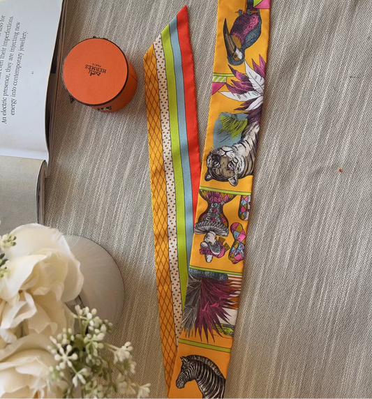 Colorful animal print belt on a wooden surface with an open book and flowers.