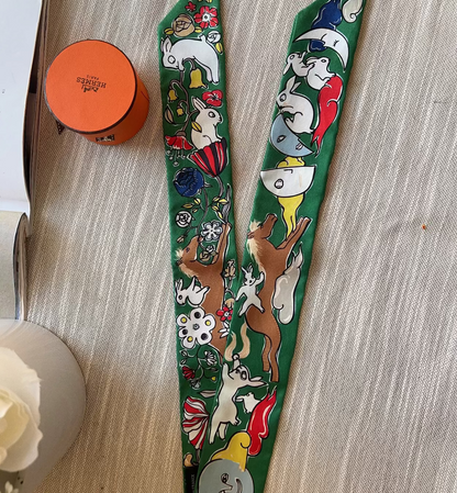 Two green decorative scarves with animal patterns on a light wooden surface.