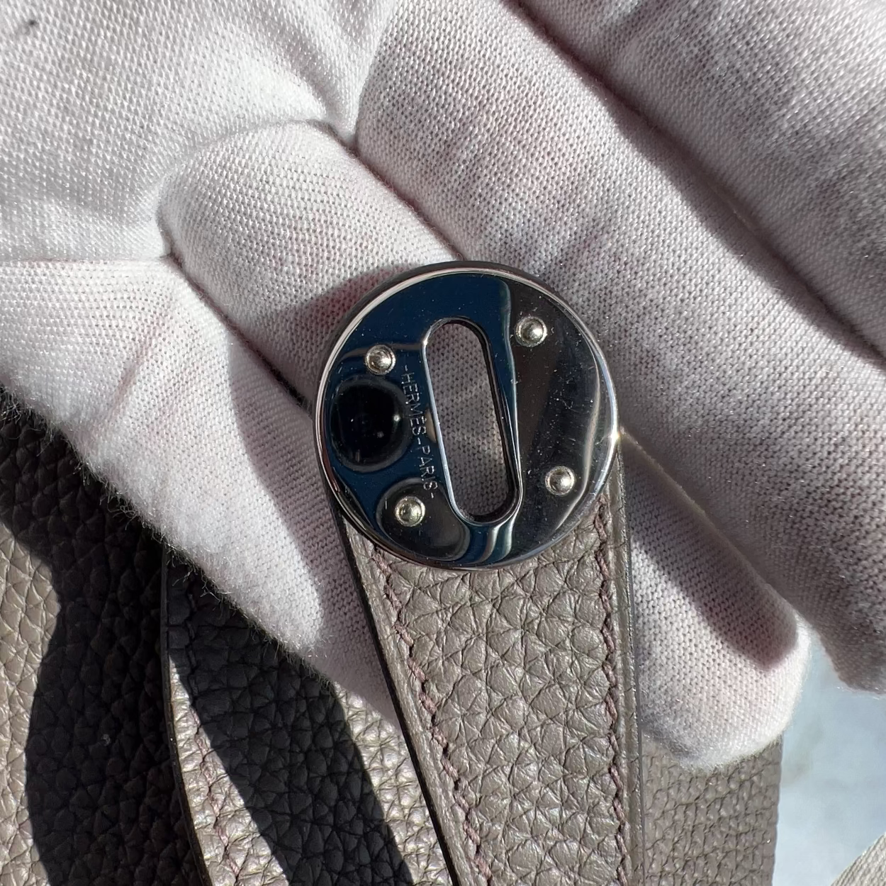 Close-up of a metal buckle on leather with a white fabric background