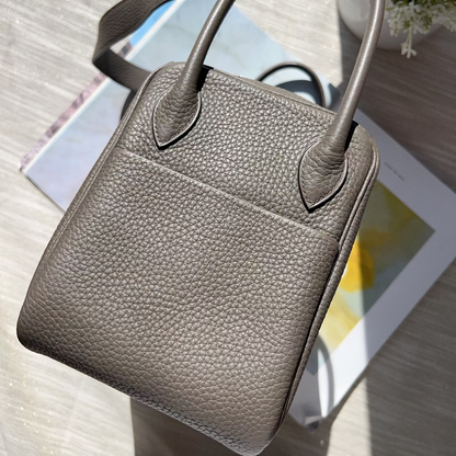 Gray leather handbag on a wooden surface with a blurred background