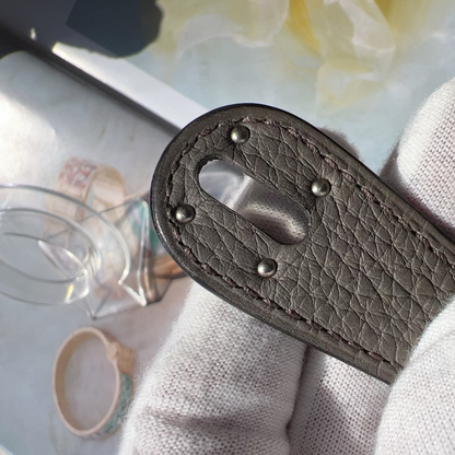 Close-up of a brown leather keychain with metal clasps on a light fabric background.