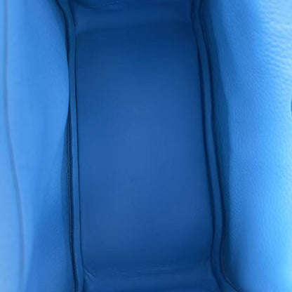 Close-up view of the interior lining of a blue leather bag, showing the smooth texture and stitched edges.