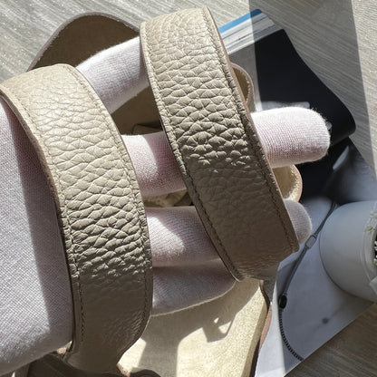 Pair of beige sandals on a light gray surface with a blurred background