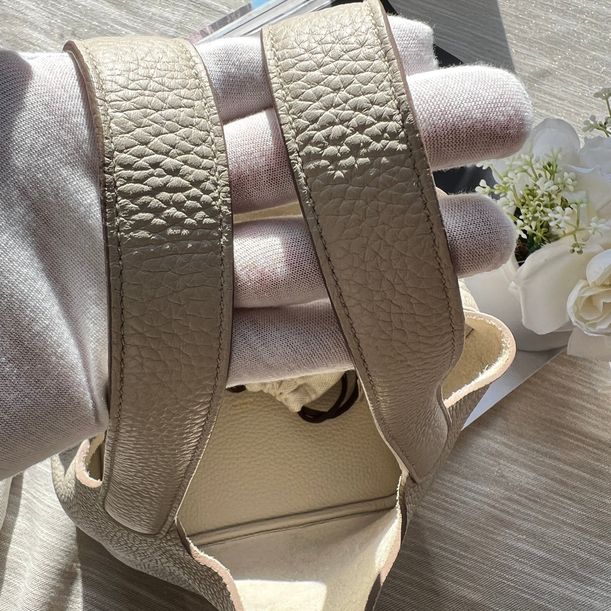 Beige sandal with textured strap on a light wooden surface