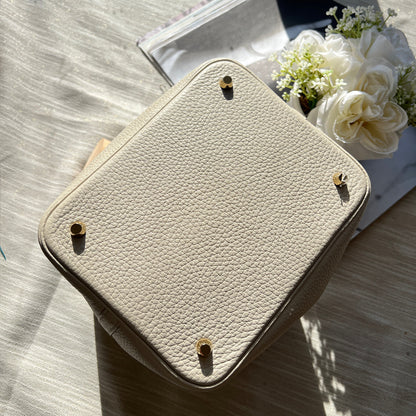 Beige leather pouch on a wooden surface with flowers and books in the background