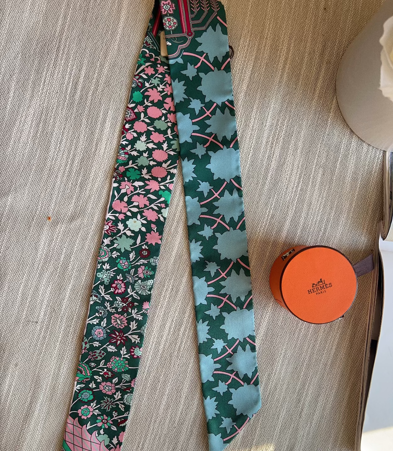 Two patterned ties and a small round box on a wooden surface