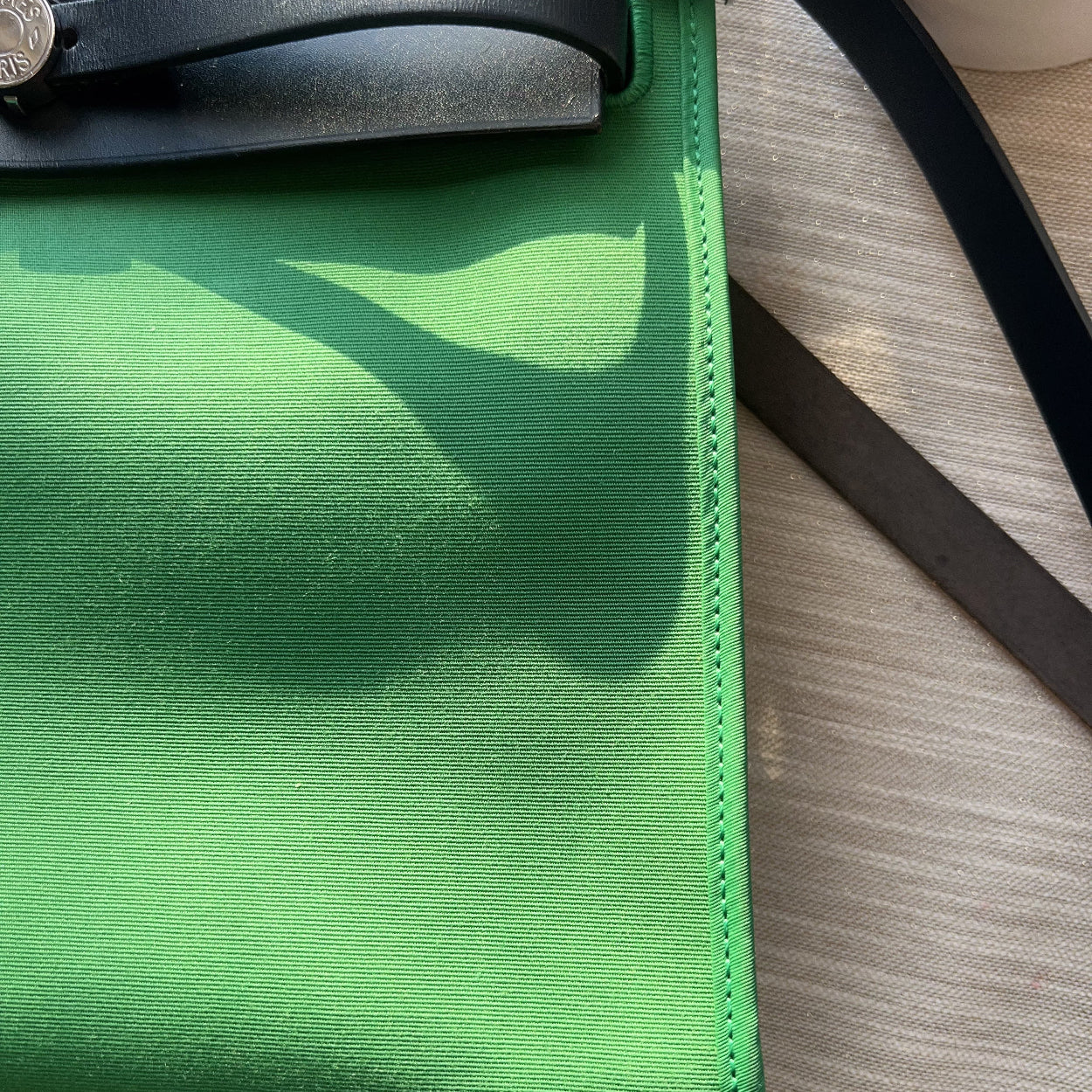 Green clutch bag with black strap on a wooden surface