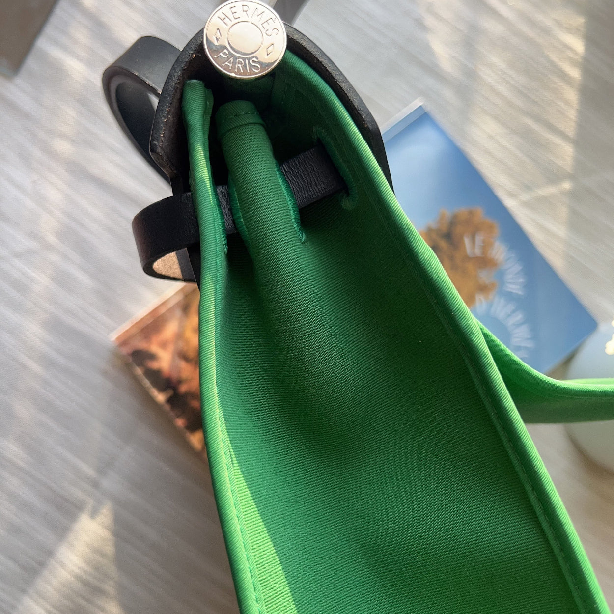 Green bag with a black strap on a reflective surface