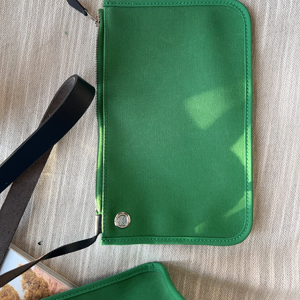 Green wallet with a strap on a light wooden surface