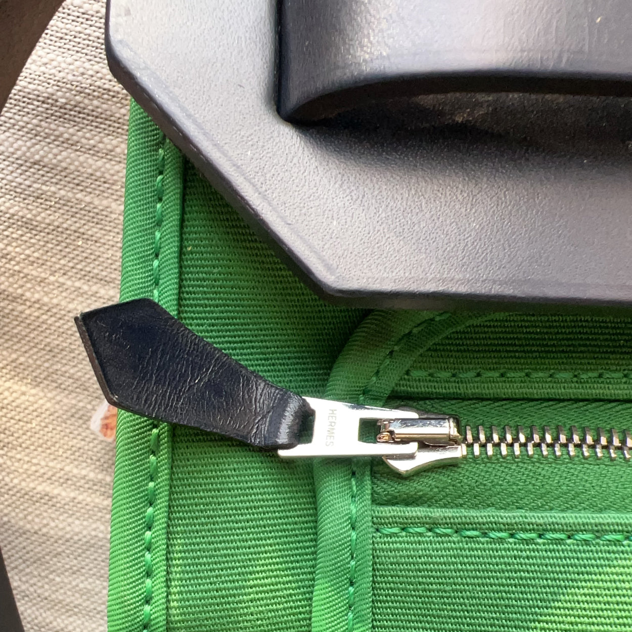 Close-up of a green bag with a black zipper pull.