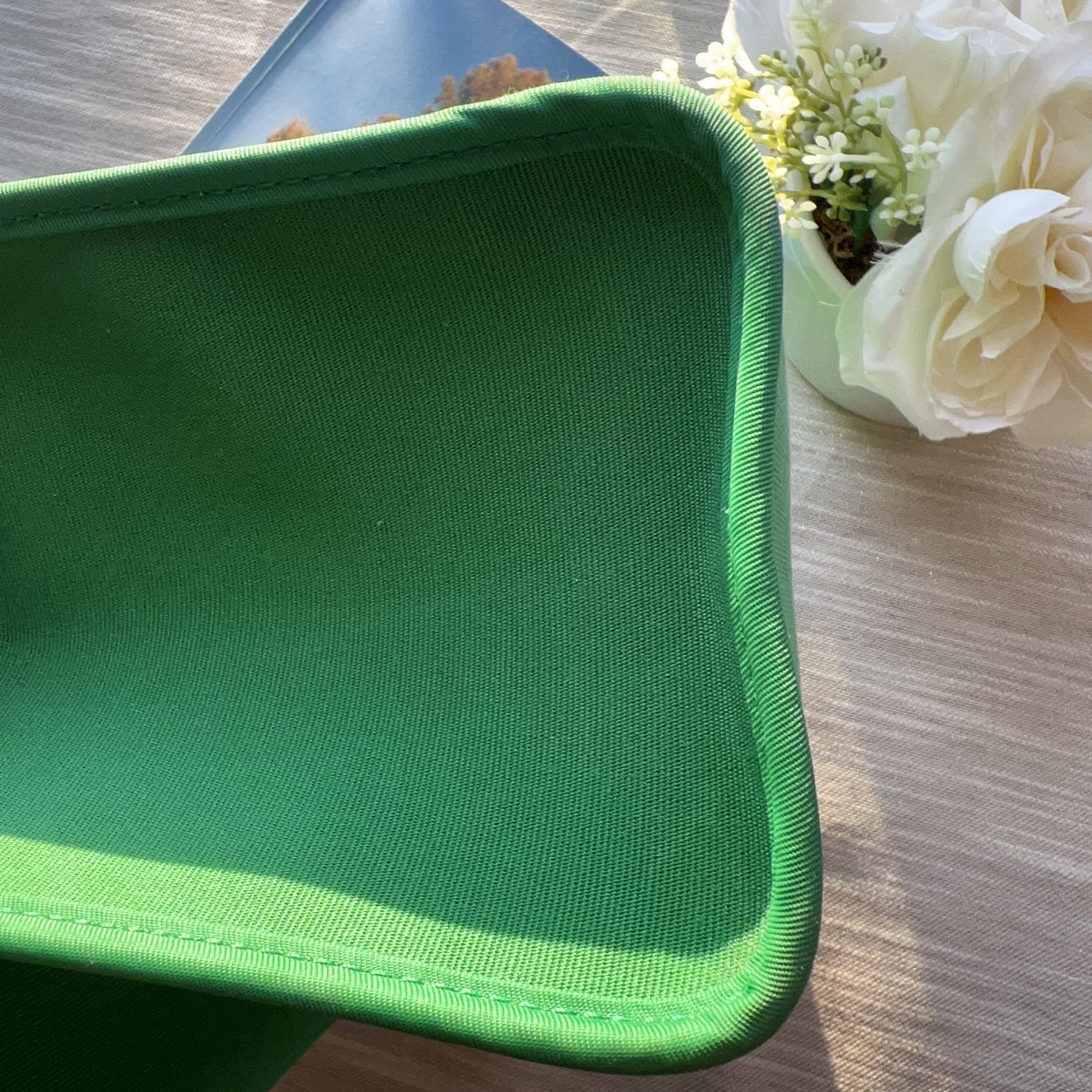 Green tray on a wooden surface with flowers in the background