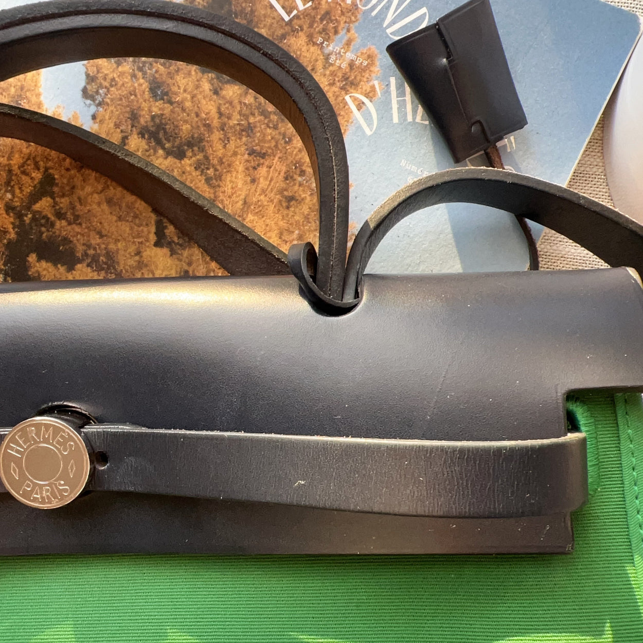 Close-up of a black metal tool with a brass emblem on a green surface.