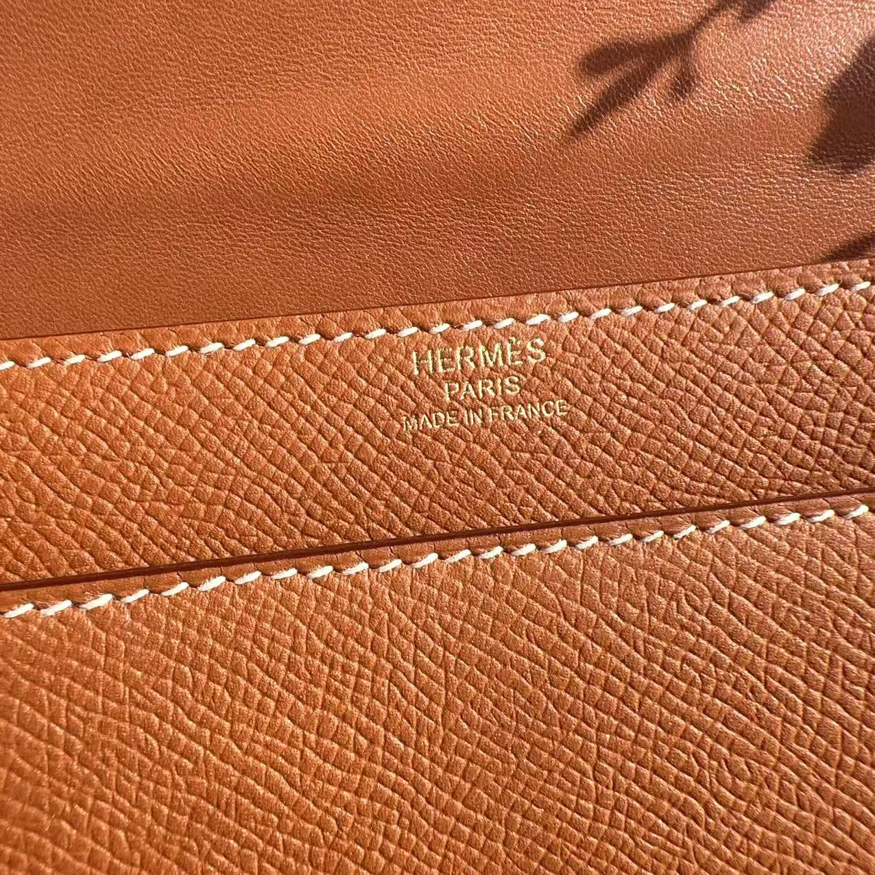 Close-up of a brown leather Hermès bag with visible branding.