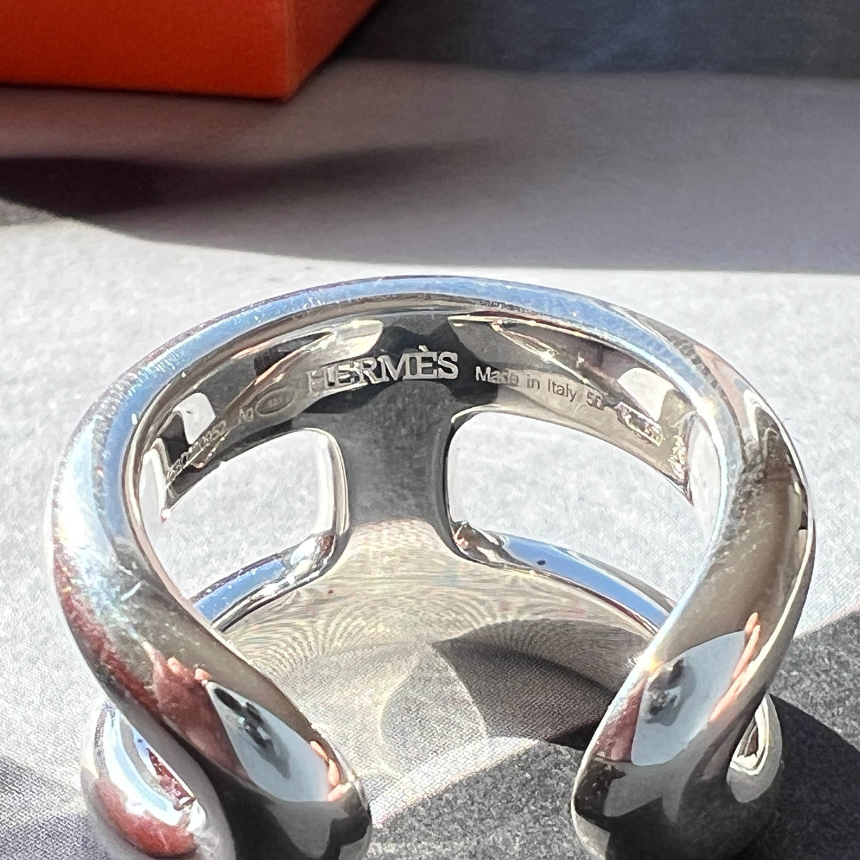 Silver Hermès bracelet on a textured surface