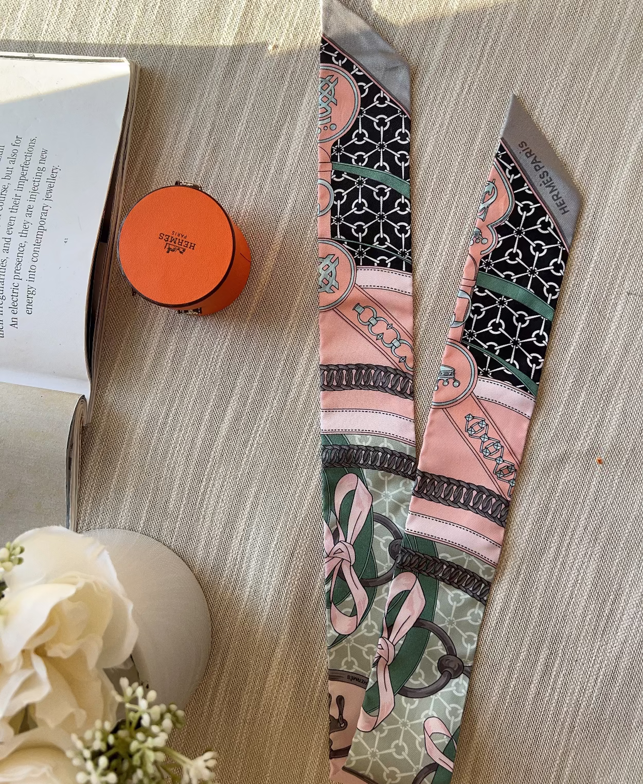 Colorful patterned tie on a wooden surface with a book and flowers.