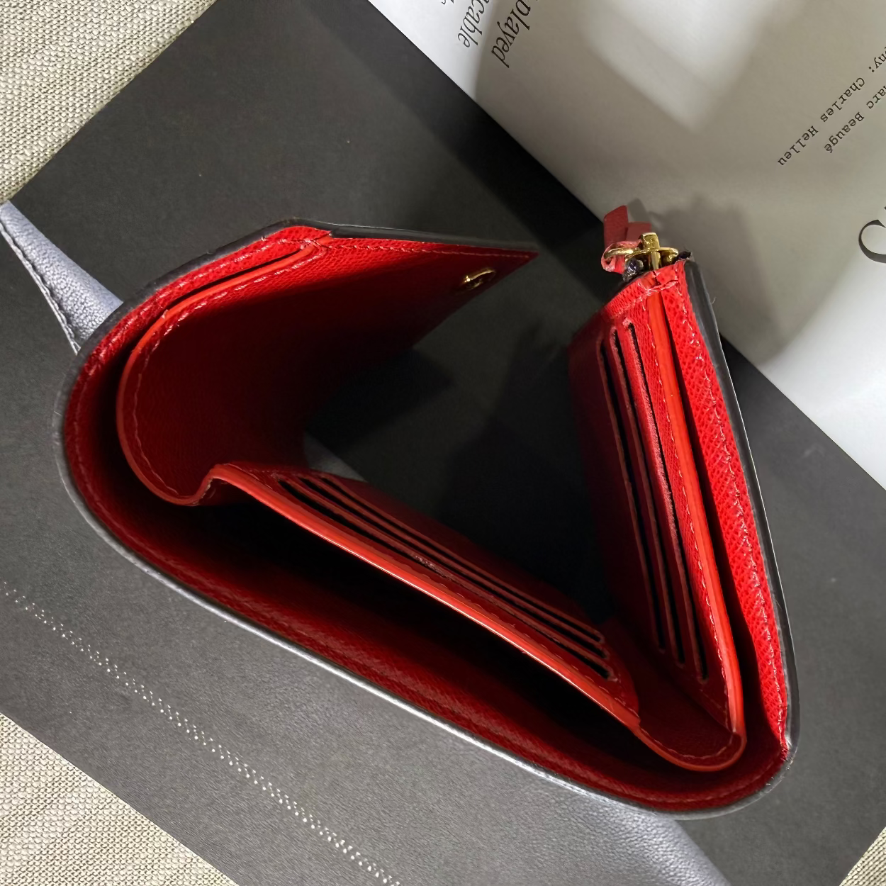 Red wallet on a textured surface with a book underneath