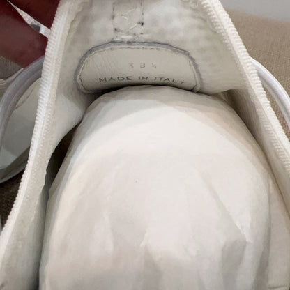 White sneaker with 'Made in Italy' label held by a hand against a neutral background