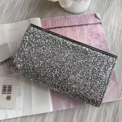 Silver glittery clutch bag on a pink surface with flowers in the background