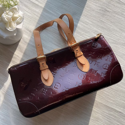 Brown handbag with tan leather straps on a light wooden surface