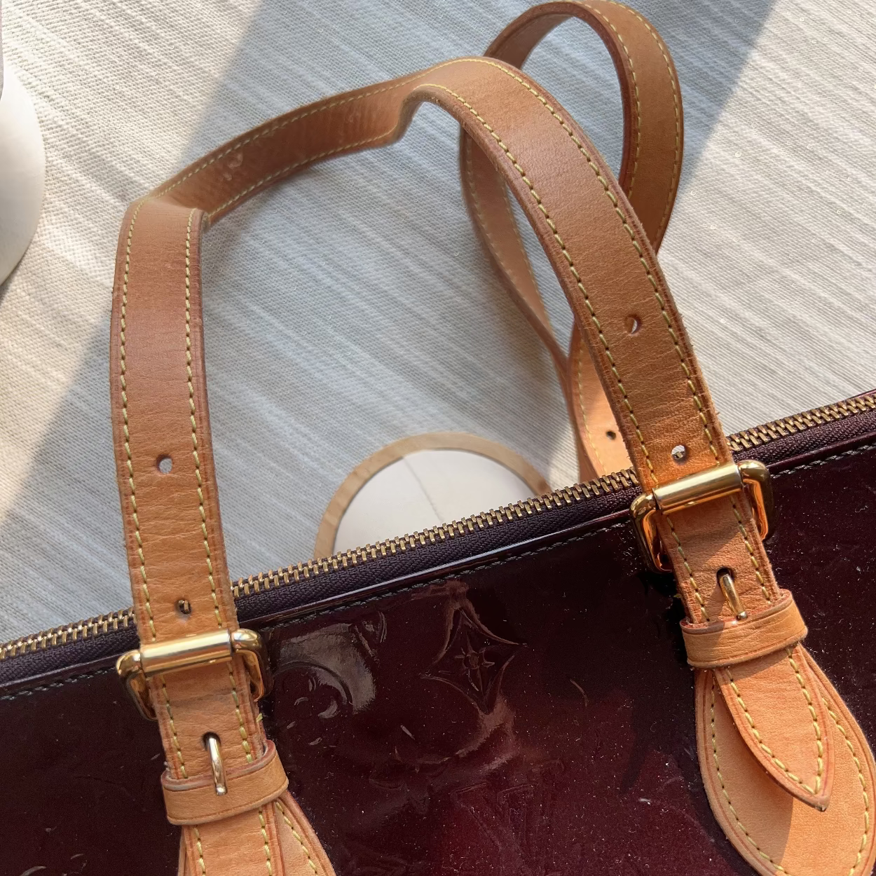 Close-up of a brown leather handle on a dark suitcase with a light background