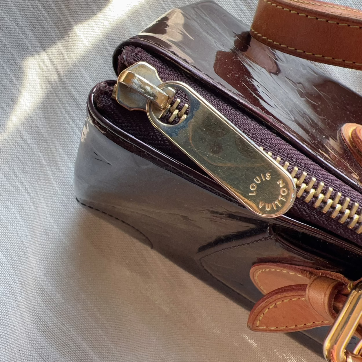 Louis Vuitton handbag with gold zipper on a textured surface