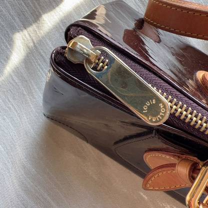 Louis Vuitton handbag with gold zipper on a textured surface