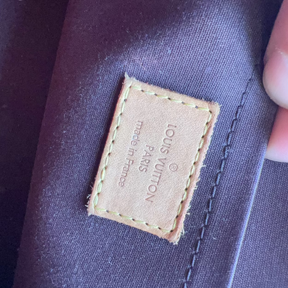 Louis Vuitton label on a garment with a hand holding it