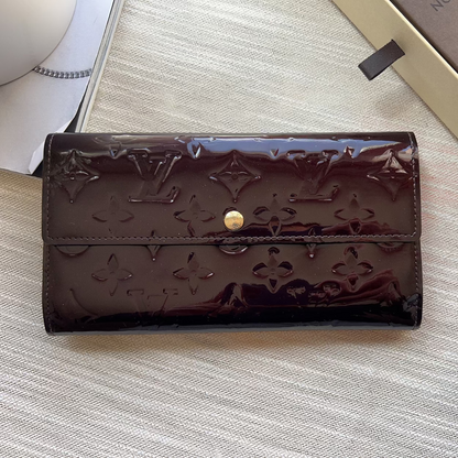 Brown leather wallet with gold emblem on a textured surface