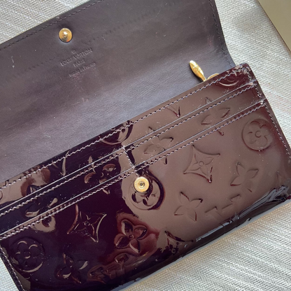 Close-up of a dark brown leather wallet with gold accents on a light fabric background