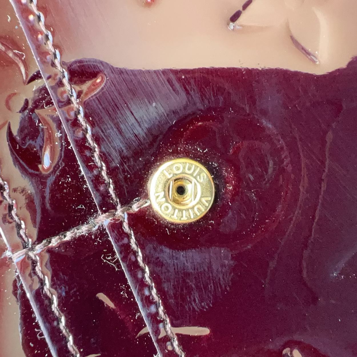 Close-up of a Louis Vuitton handbag with a gold turnlock clasp.