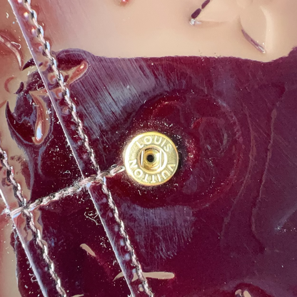 Close-up of a Louis Vuitton handbag with a gold turnlock clasp.