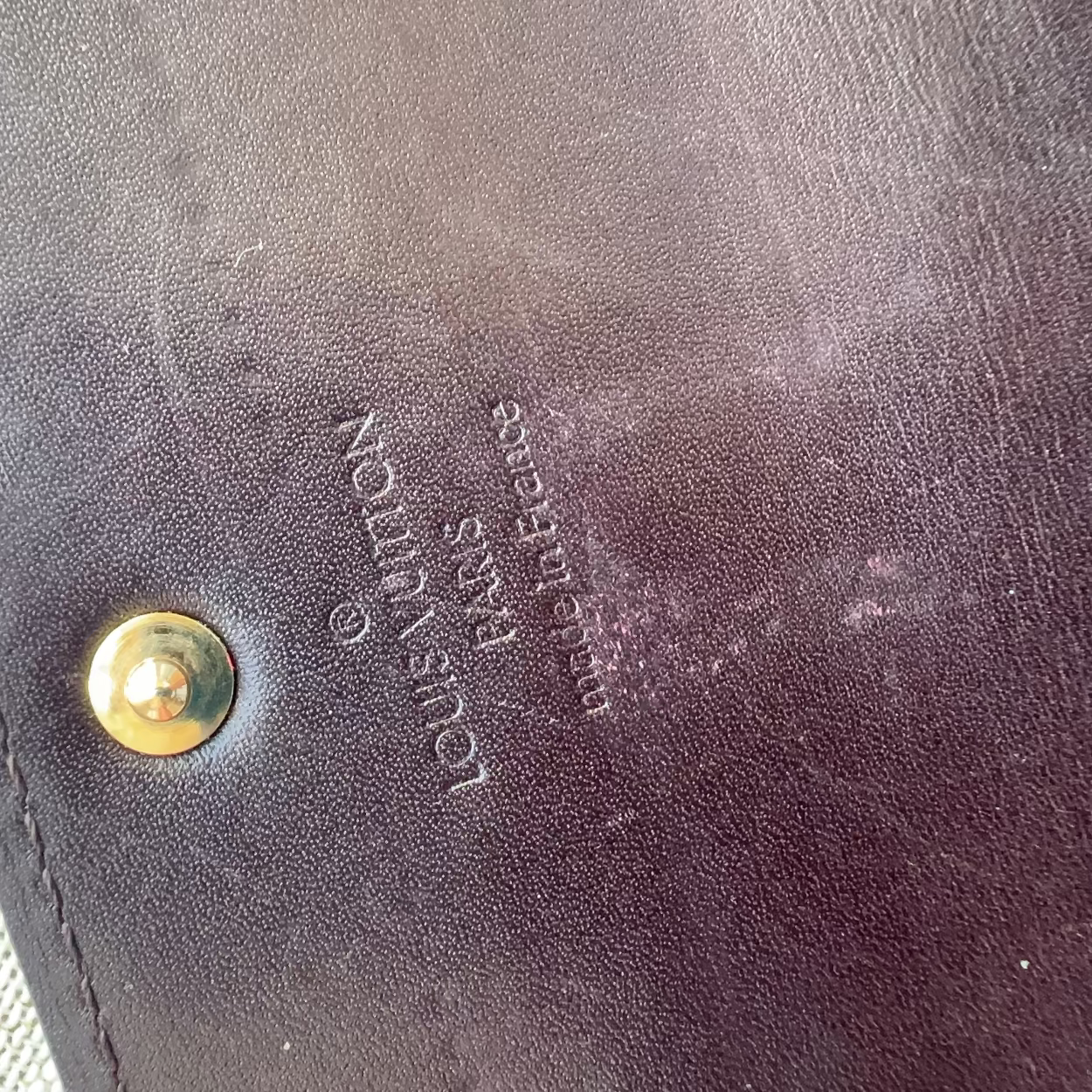 Close-up of a Louis Vuitton wallet with gold logo and text.