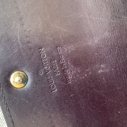 Close-up of a Louis Vuitton wallet with gold logo and text.