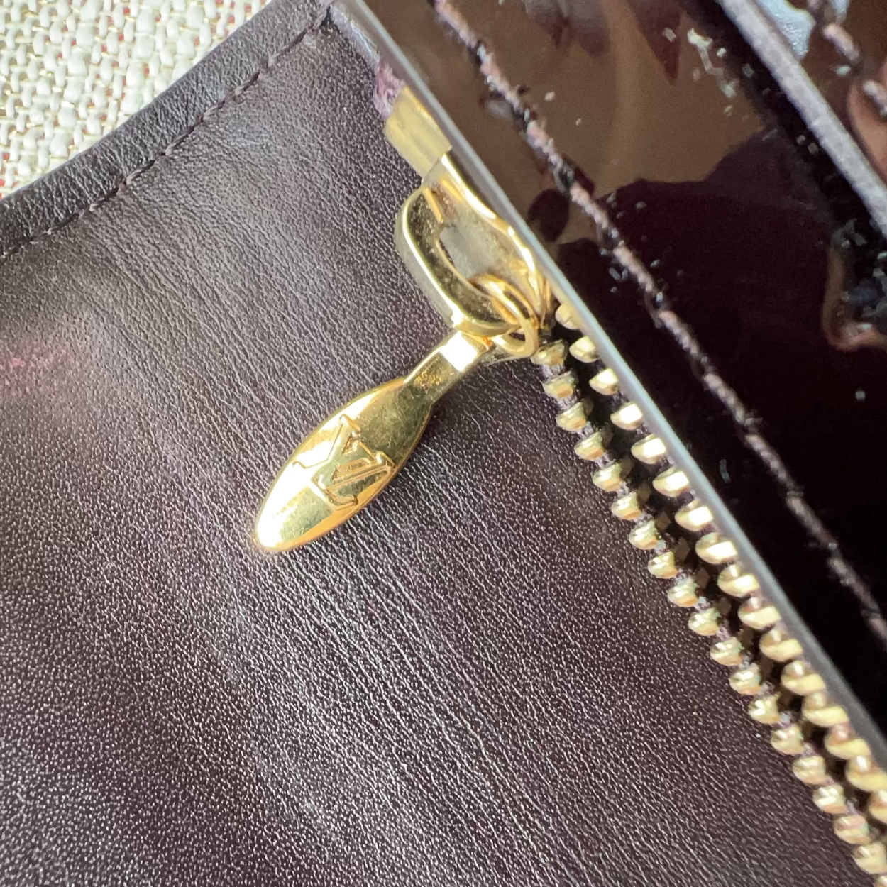 Close-up of a brown leather wallet with a gold zipper pull.