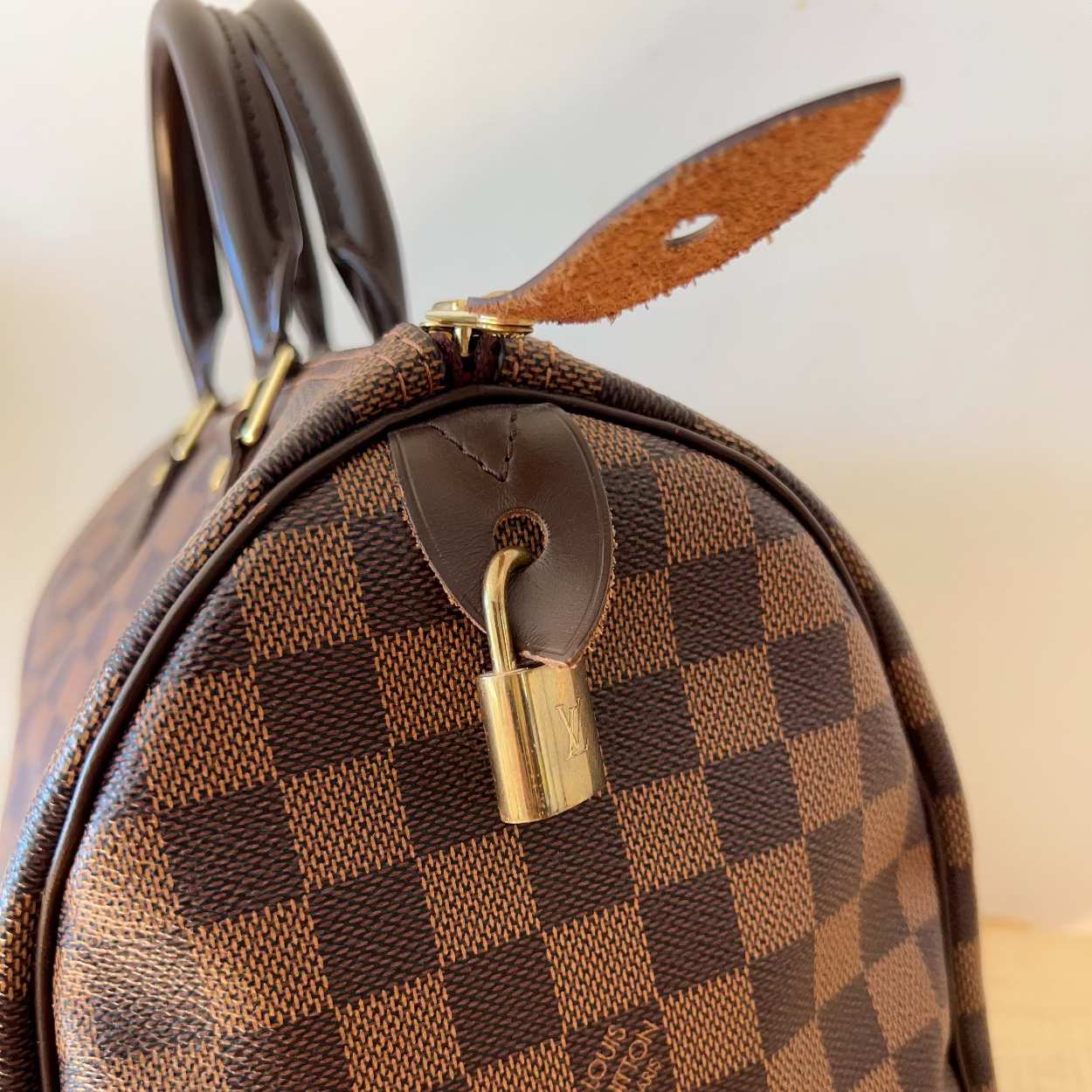 Brown checkered handbag with a gold lock on a light background