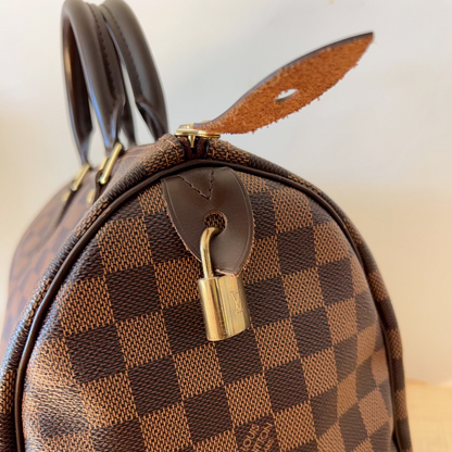 Brown checkered handbag with a gold lock on a light background