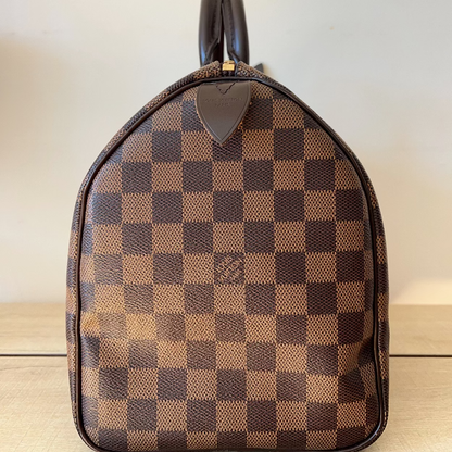 Brown checkered handbag on a wooden surface with a light background