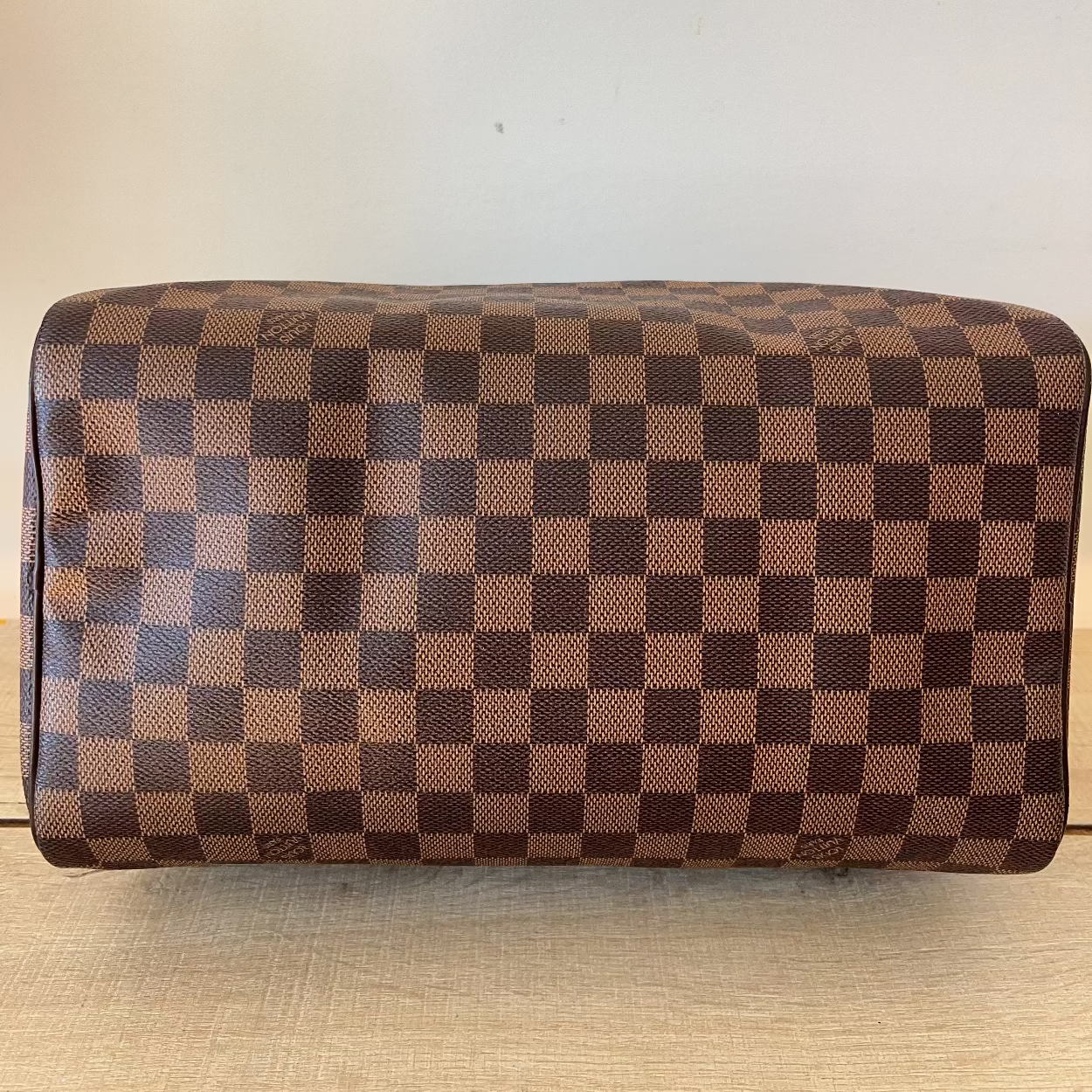 Brown checkered handbag on a light wooden surface
