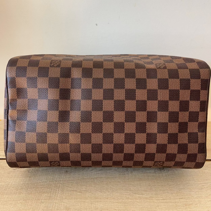 Brown checkered handbag on a light wooden surface