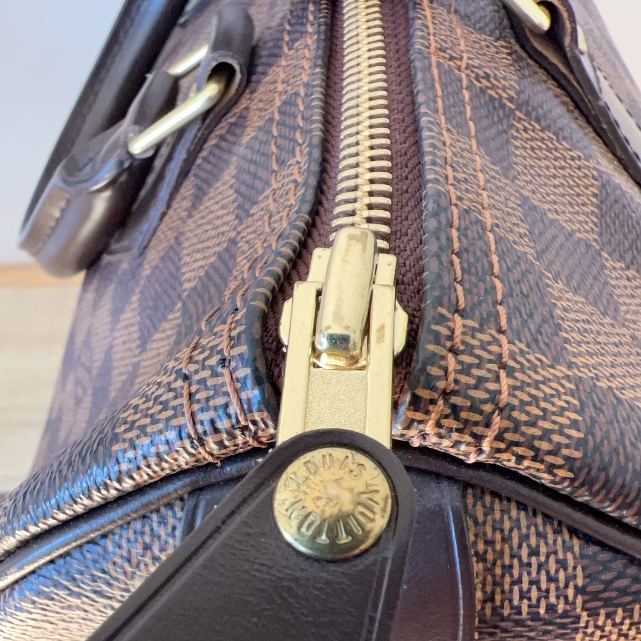 Close-up of a patterned handbag with a gold zipper and brand logo.