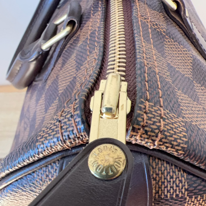 Close-up of a patterned handbag with a gold zipper and brand logo.